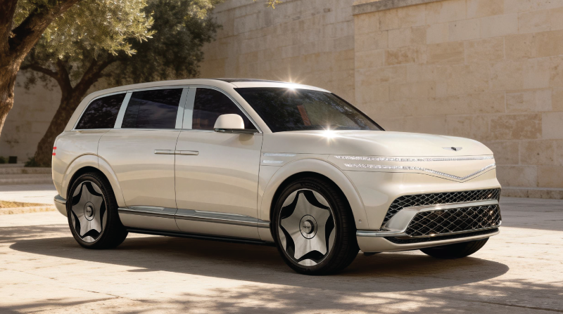 Cream-colored Genesis Neolun Concept SUV with distinct split headlights and turbine-style wheels parked on a sunny paved surface.