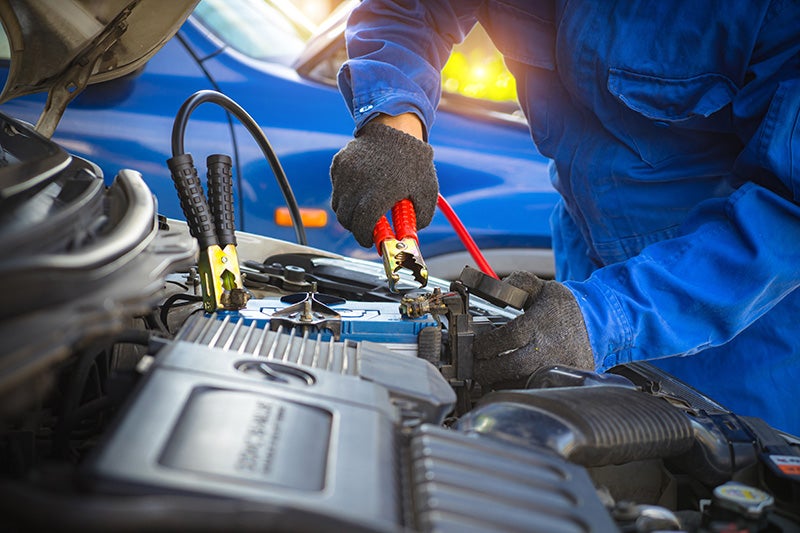 Technician servicing a vehicle battery as part of Genesis maintenance and repair services.